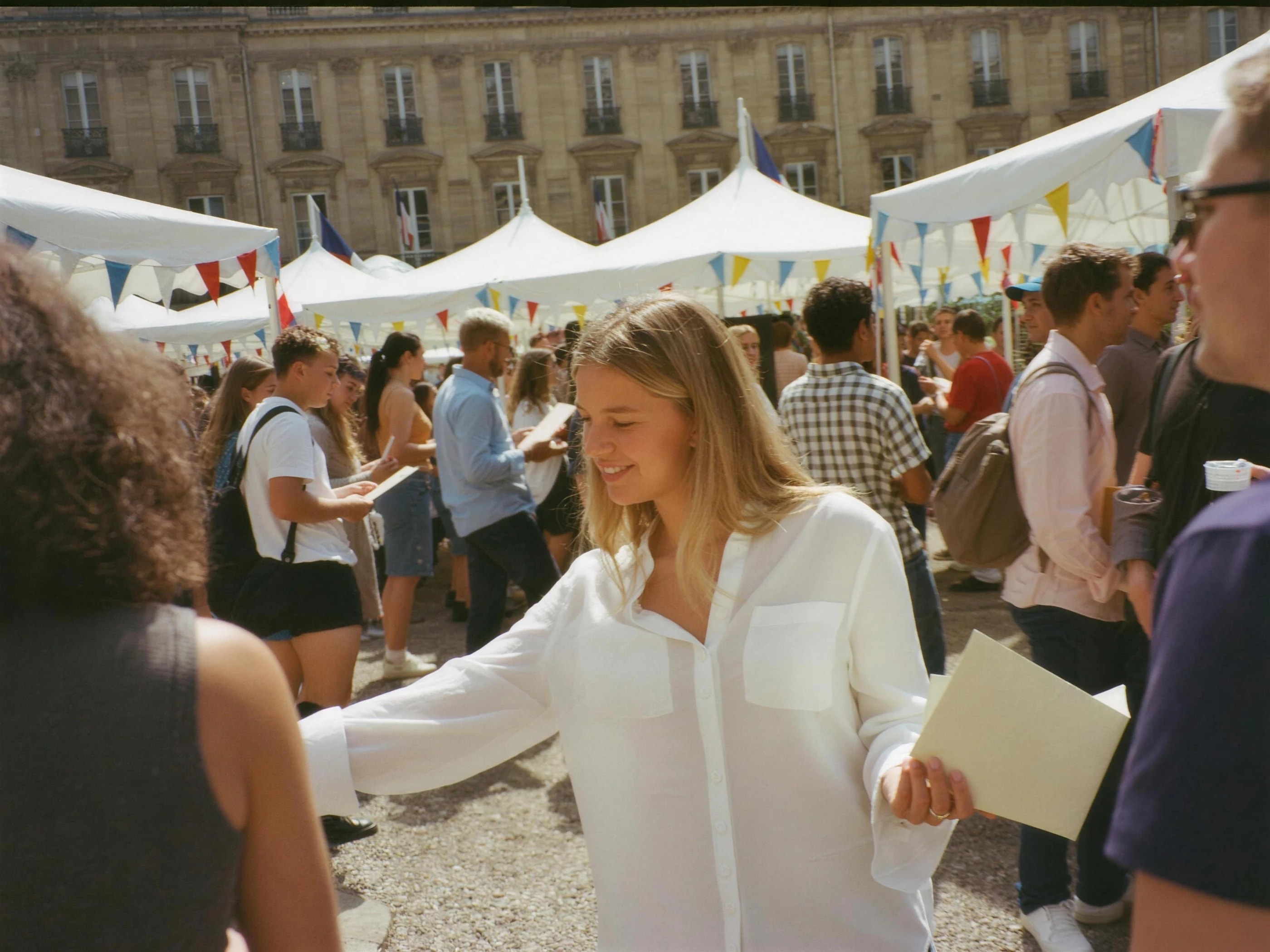 Des étudiantes et des étudiants circulent entre les barnums d'un forum des associations, dans la cour ensoleillée d'un campus.